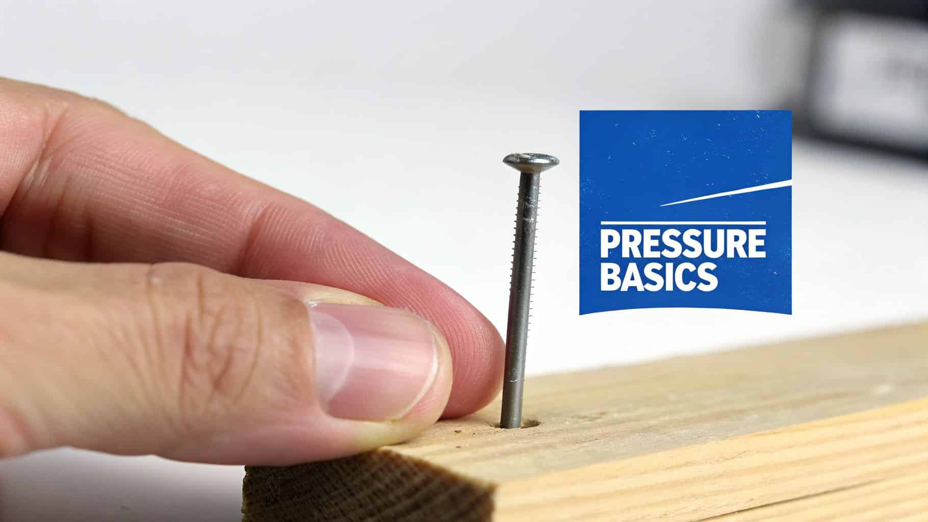 A hand holds a nail partially inserted into a wooden board, with a 'PRESSURE BASICS' logo.