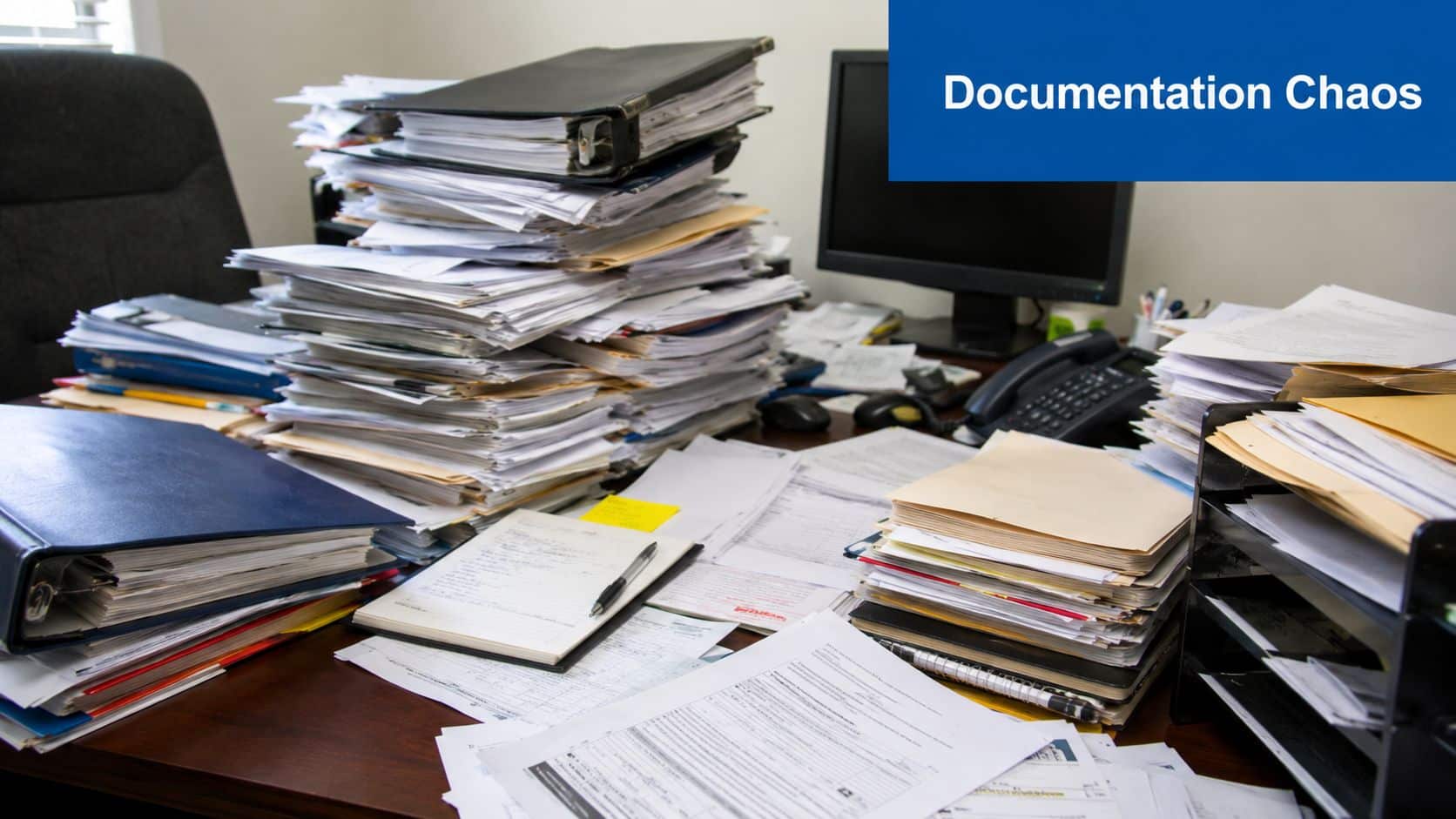 A messy office desk covered with stacks of paperwork, documents, and folders representing disorganized office administration.