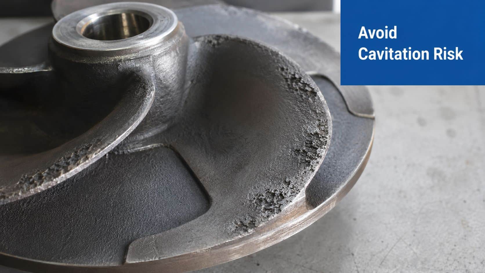 A close-up view of a damaged metal industrial pump impeller showing clear signs of surface cavitation wear.