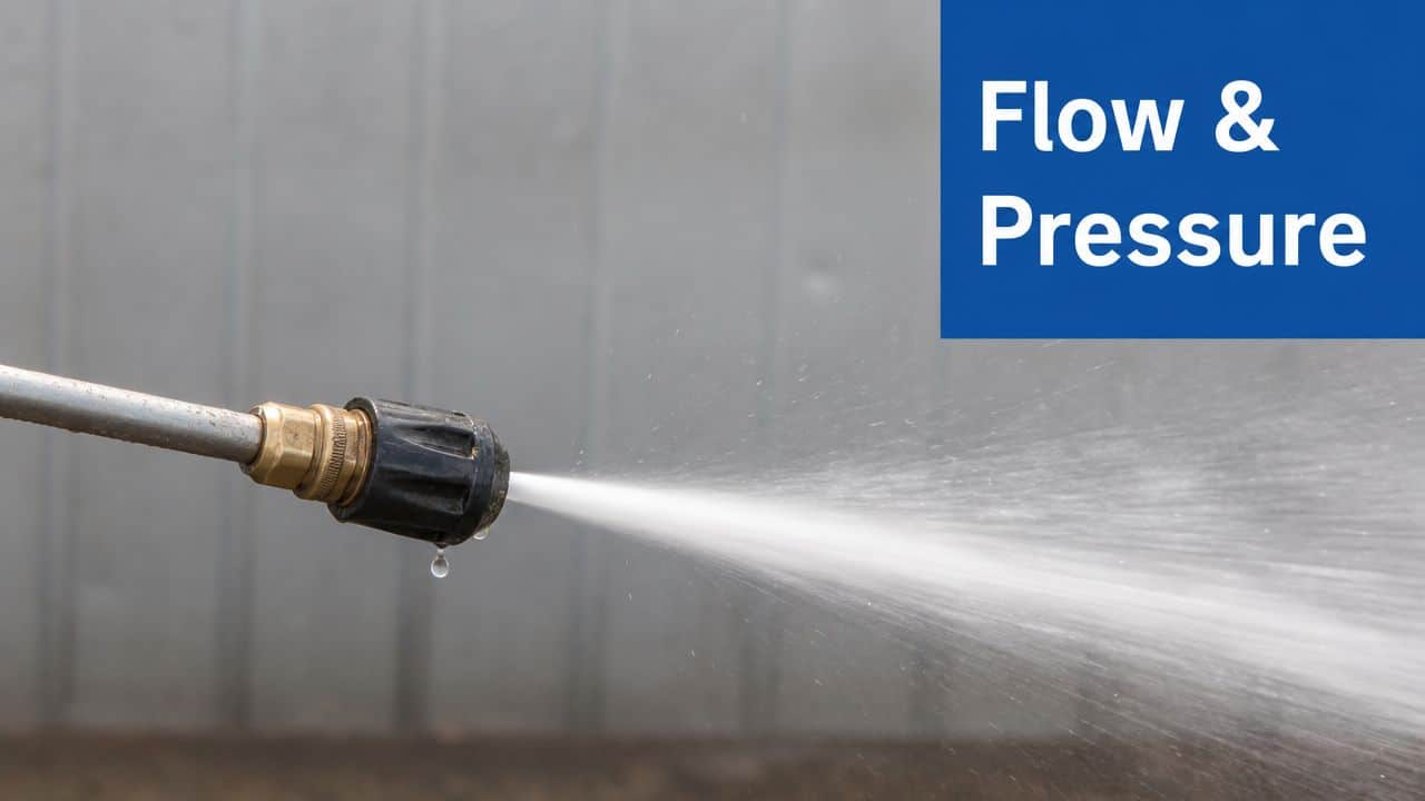 A close-up view of a metal pressure washer nozzle spraying a powerful stream of water.